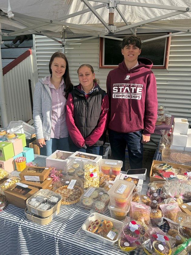 Dalby Devils Samara Mittelstadt (left), club captains Mia Deem and Cooper Collins man the bake sale to raise money for McGrath Foundation breast cancer nurses in Dalby. (Photo : QRL)